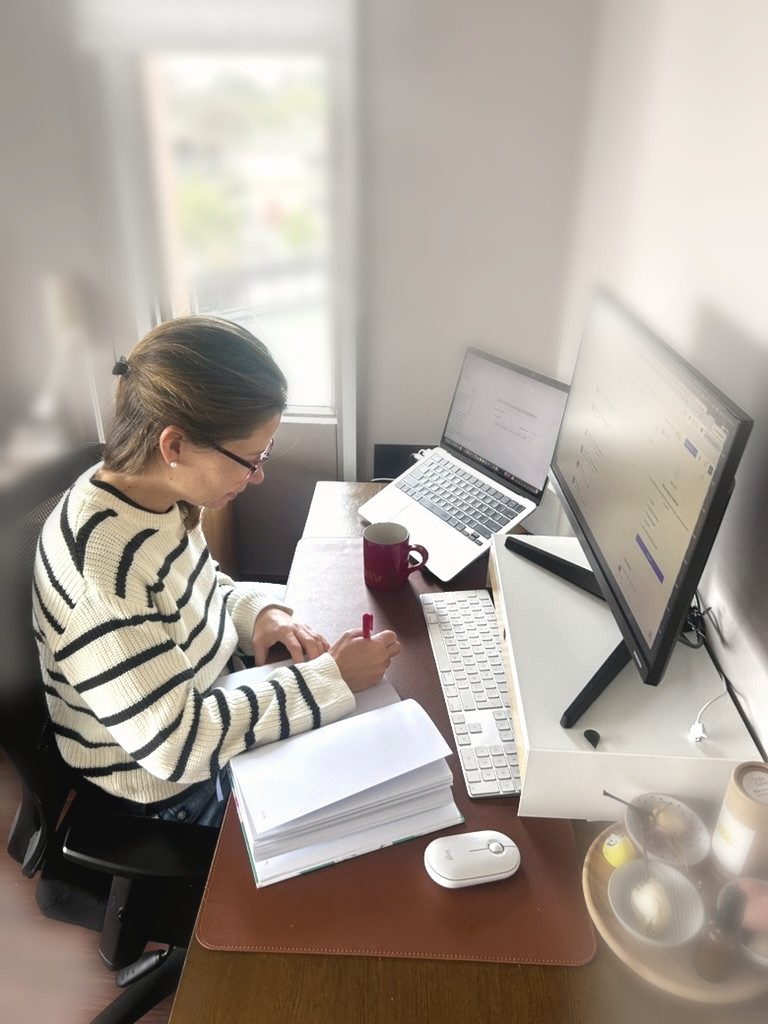 Alejandra Camacho Rincón trabajando en su escritorio, con un cuaderno abierto y su computador